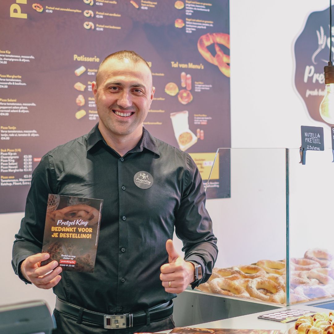 Een teamlid van Pretzel King in de bakkerij naast de versgebakken pretzels